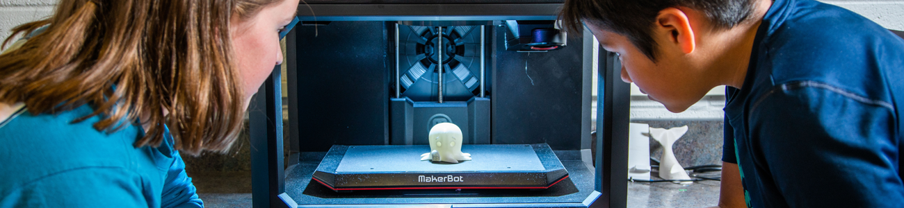 two students watch 3d printer 